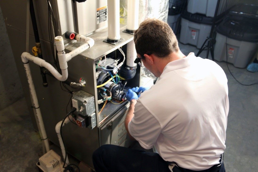 A man is working on an air conditioner in a garage.