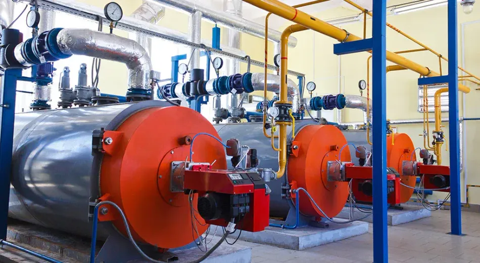A row of boilers and pipes in a factory.