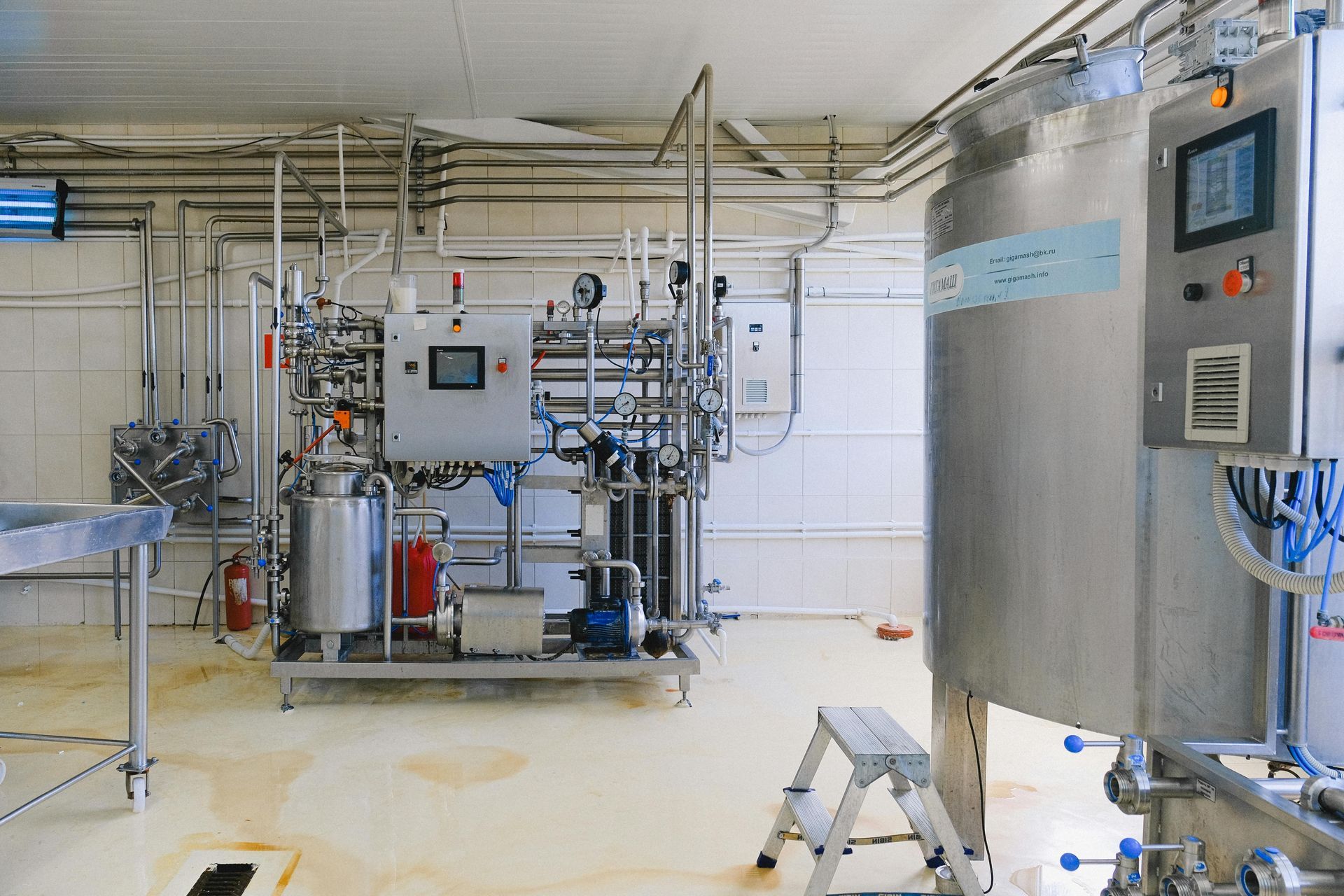 Industrial equipment and control panels in a bright cleanroom with stainless steel machinery and piping