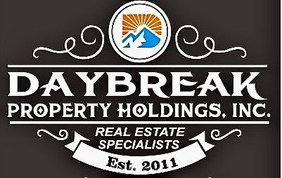 A woman is sitting at a desk with a laptop and a vase of flowers.