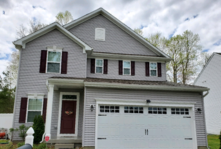 A large white house with a red door and a white garage door.