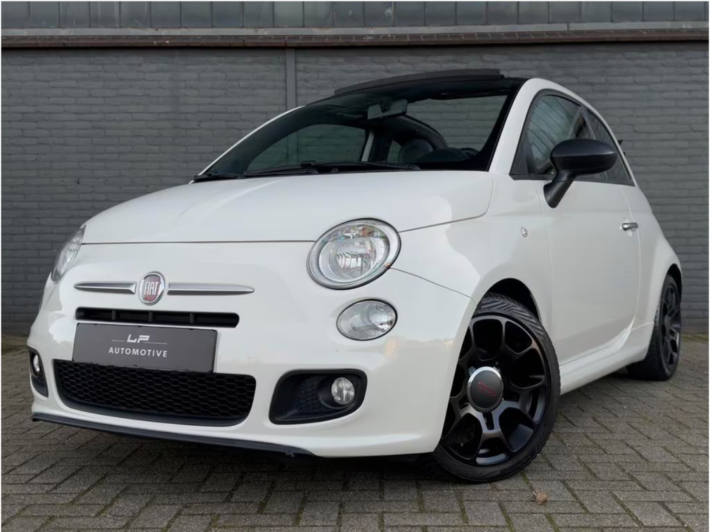 Witte Fiat 500 met zwarte accenten geparkeerd voor een grijze muur.