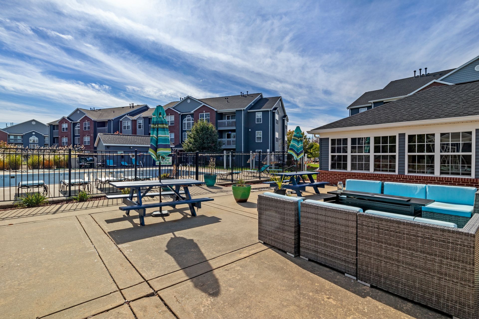 A patio area with picnic tables and a couch in front of a building.