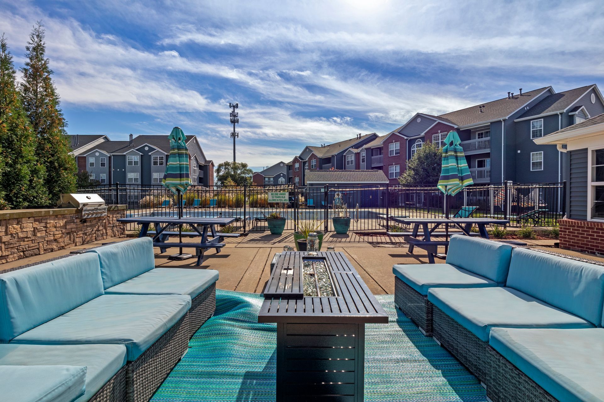 A patio area with a table , couch , and umbrellas.