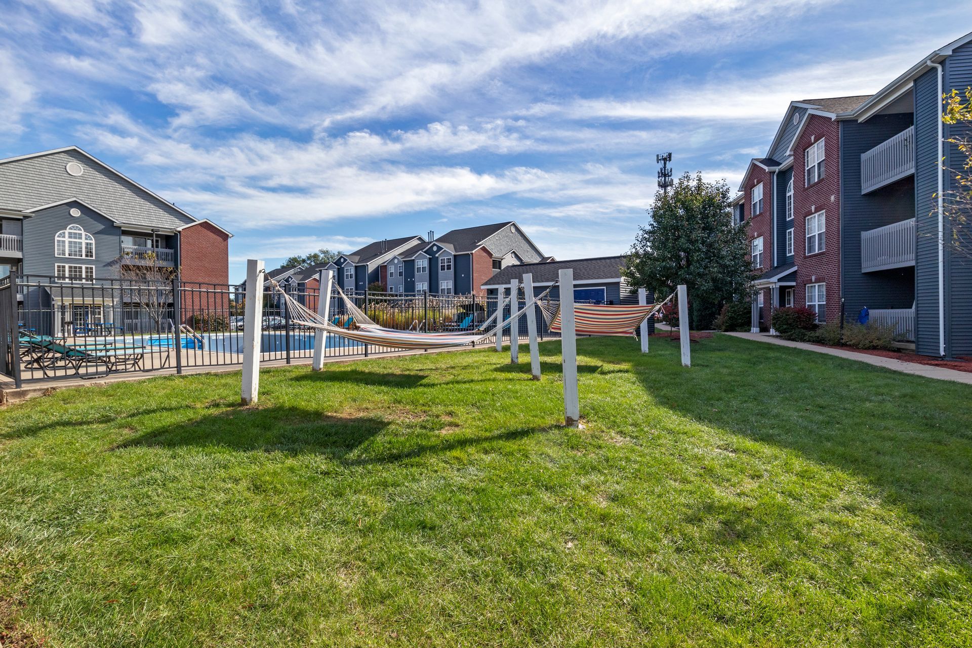 There is a playground in the middle of the grass in front of a building.