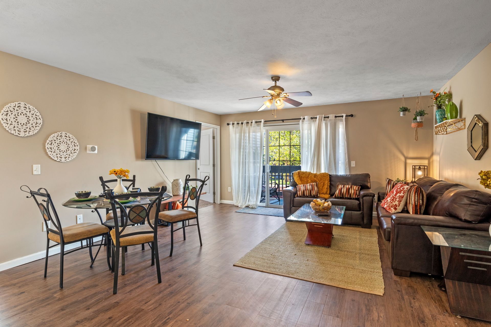 A living room with a couch , table and chairs and a flat screen tv.