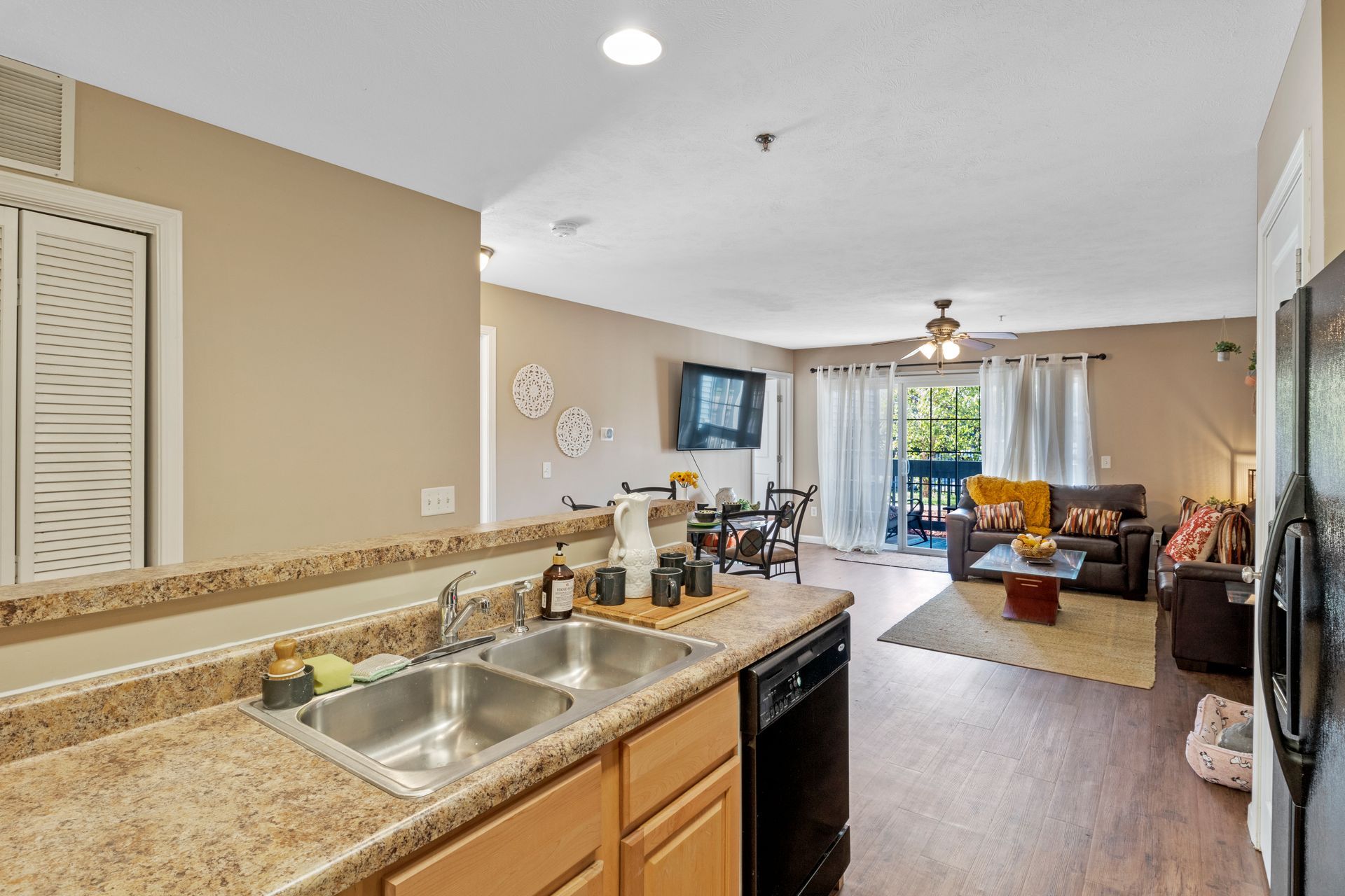 A kitchen with two sinks , a refrigerator , and a living room.