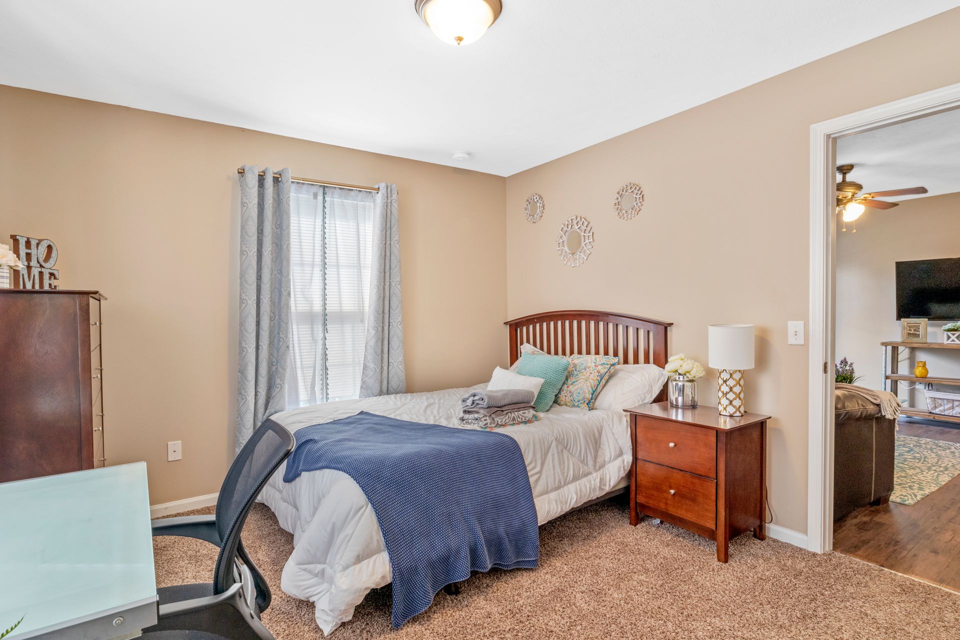A bedroom with a bed , nightstand , desk and chair.