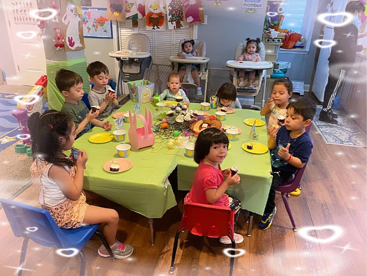 Children eating cupcakes at a table with a green tablecloth in a brightly decorated room.