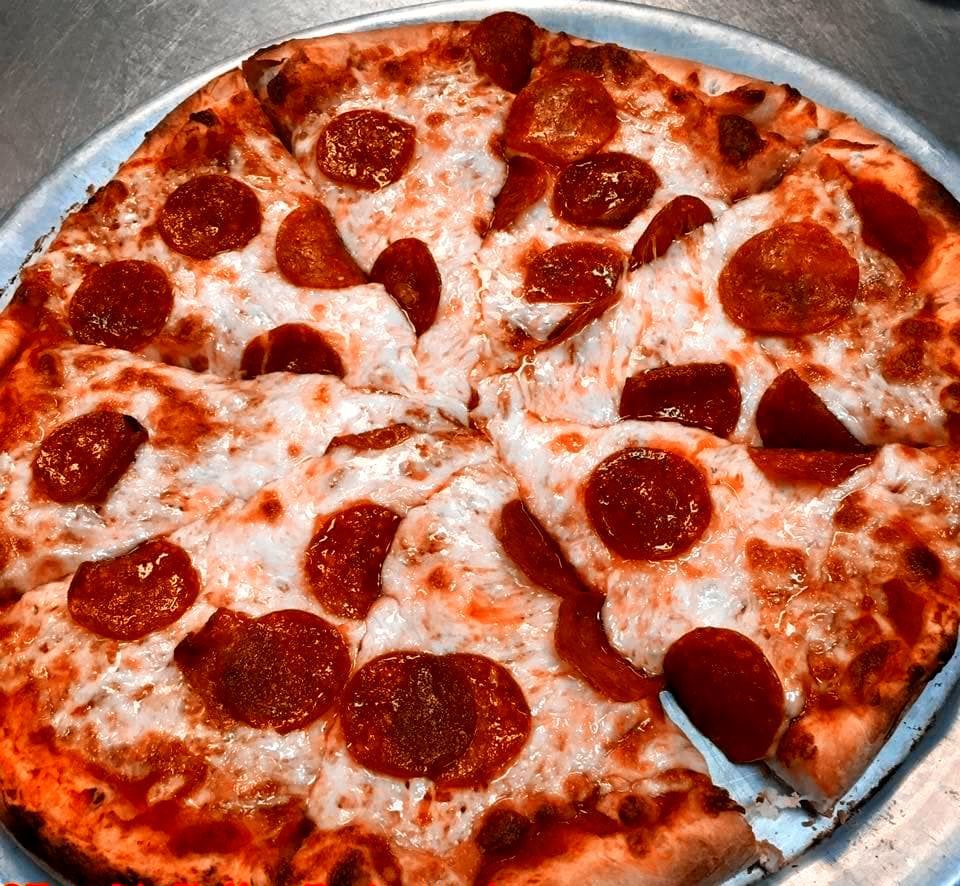Two women enjoying pizza and food with wine.