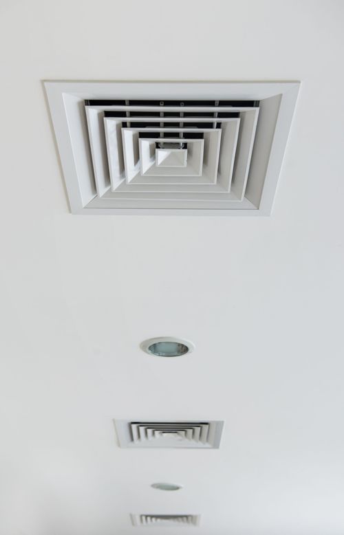 White ceiling with a large square air vent, a recessed light, and smaller vents arranged in a line.