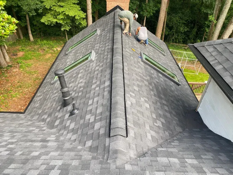 Two electricians working on an electrical panel outside a building. One holds a cable.