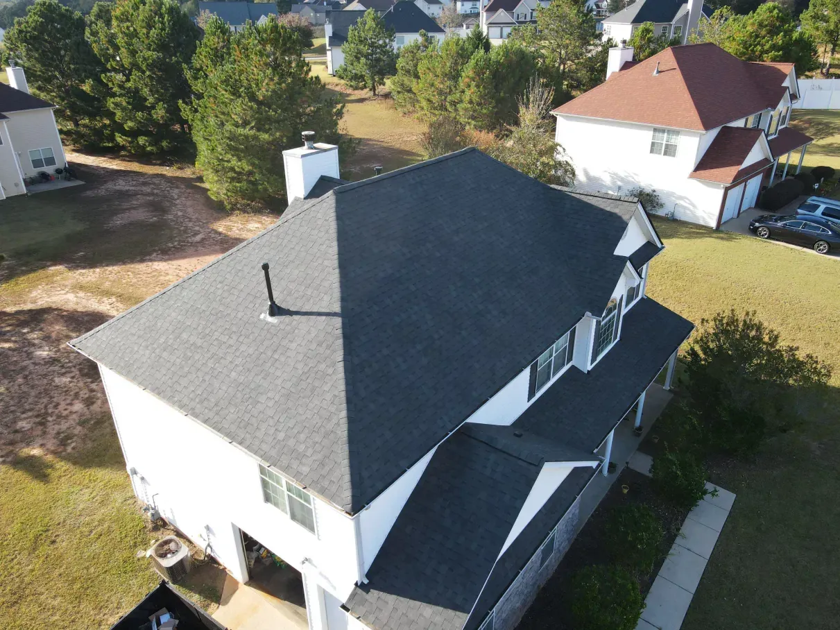 Aerial view of a white house with a dark gray roof in a suburban setting.