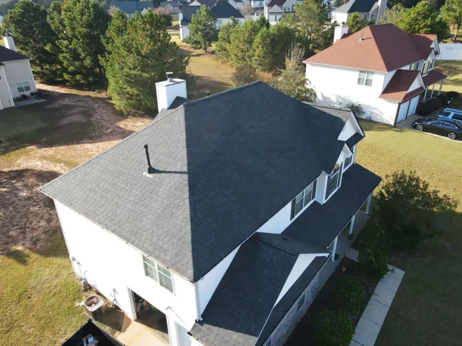 Aerial view of a white house with a dark gray roof in a suburban setting.