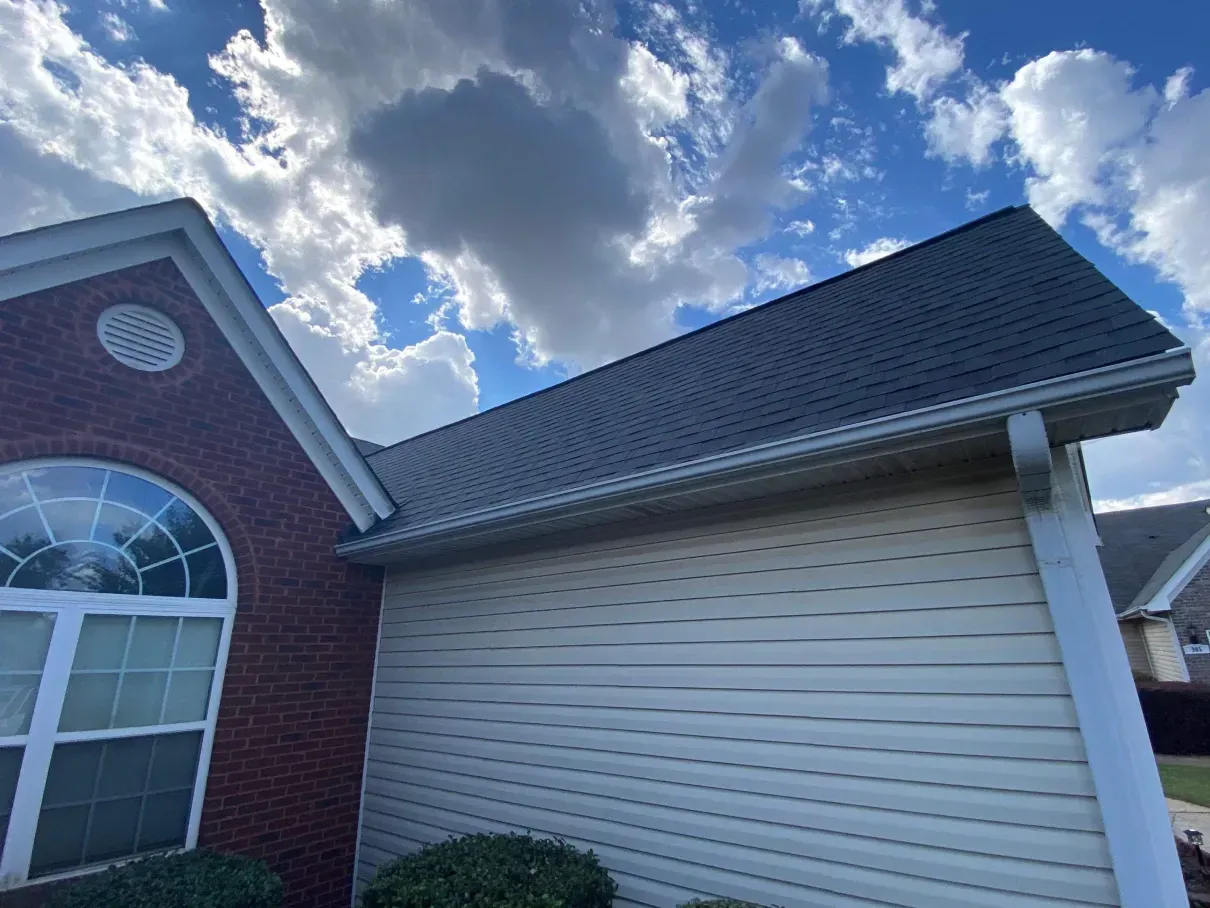 Two electricians working on an electrical panel outside a building. One holds a cable.
