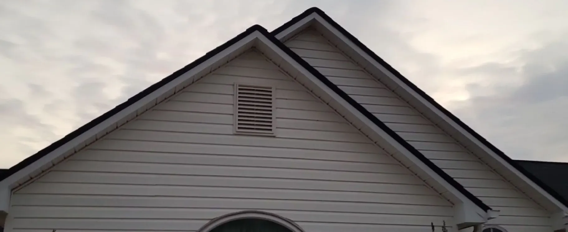 Trench dug in a grassy yard, leading to a house with black siding, and an electrical box.