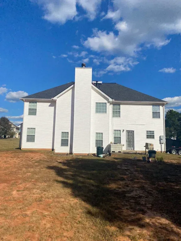 Two electricians working on an electrical panel outside a building. One holds a cable.