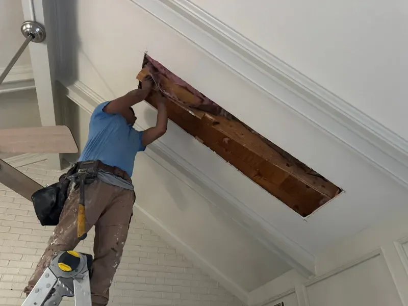 Person on ladder removes wooden structure from ceiling.