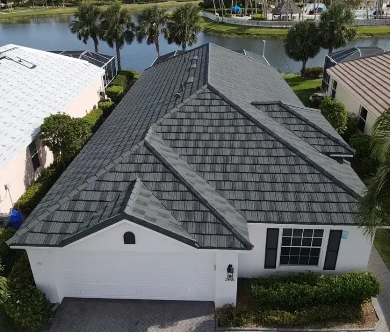 White house with black roof and chimney under a blue sky, with a ladder leaning against the side.