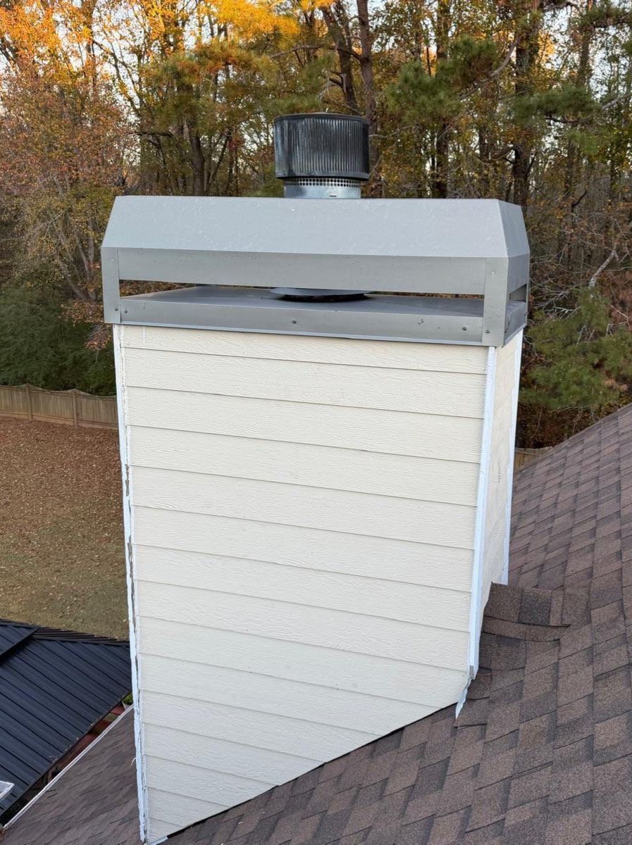 A person digs a trench in a backyard near a small excavator, a tree, and a house.
