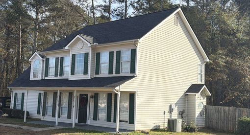 House exterior with brick, siding, and dark roof under a cloudy blue sky.