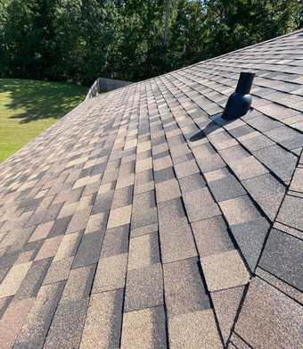White and brown siding section of a house against a red brick wall; ladder visible.