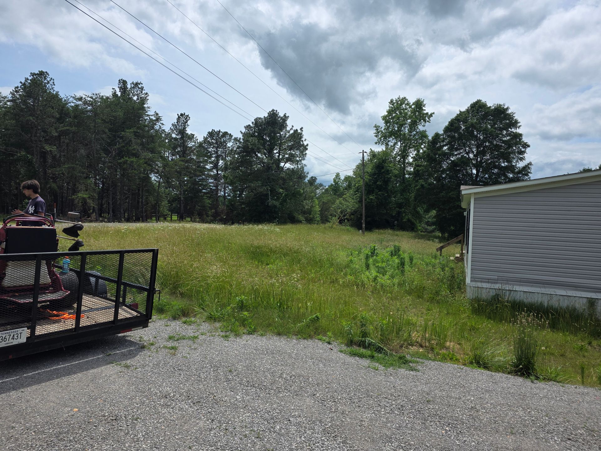 A trailer is parked on the side of the road next to a grassy field.