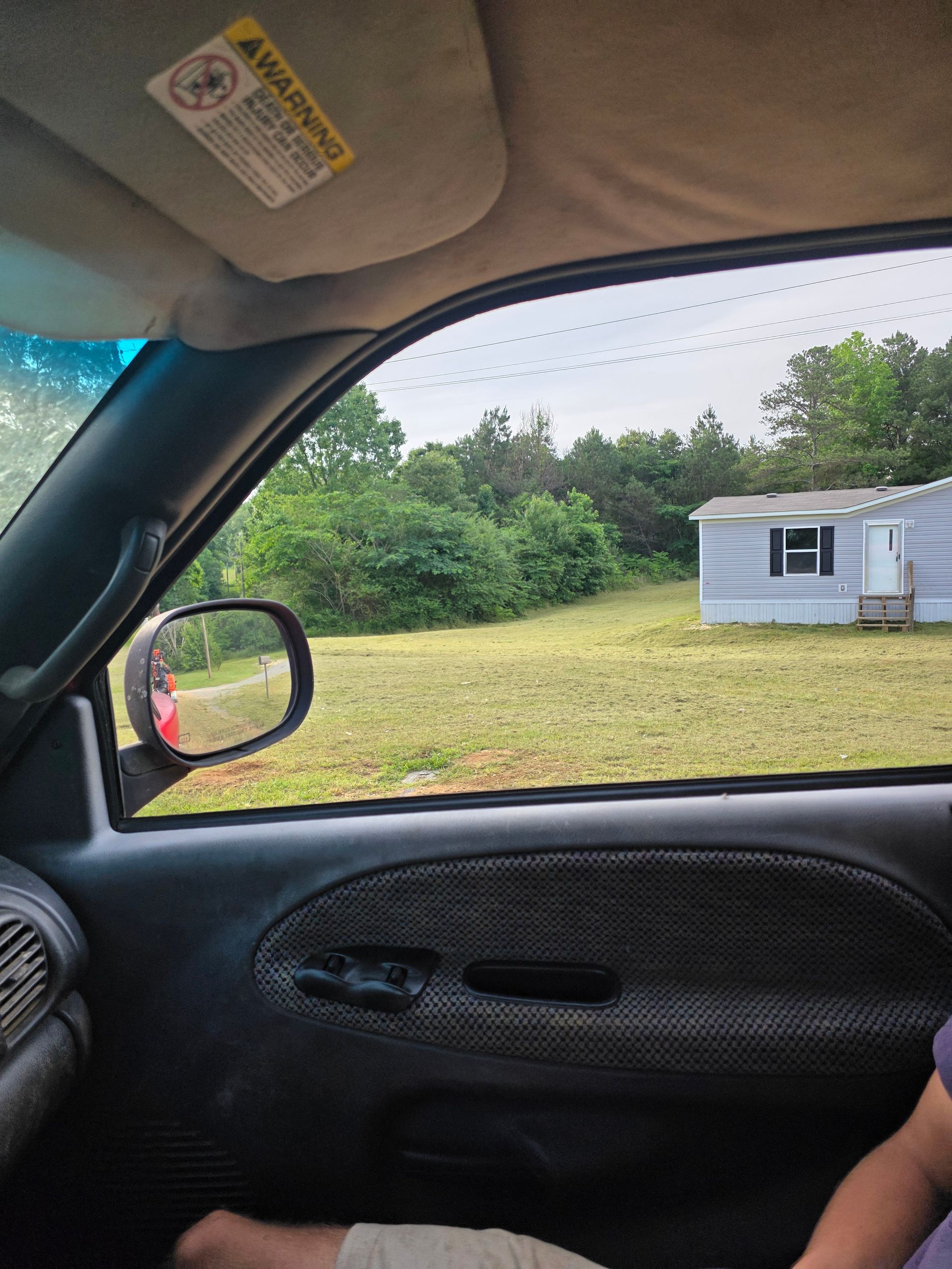 A person is sitting in a car looking out the window at a house.
