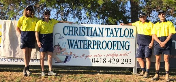 Employees at Christian Taylor Waterproofing standing in front of sign