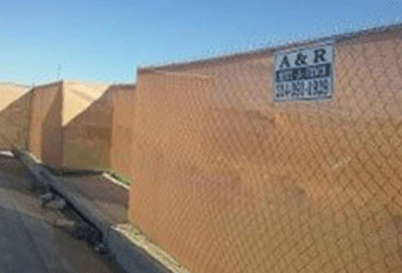 Brown mesh fence with A&R sign against a blue sky.