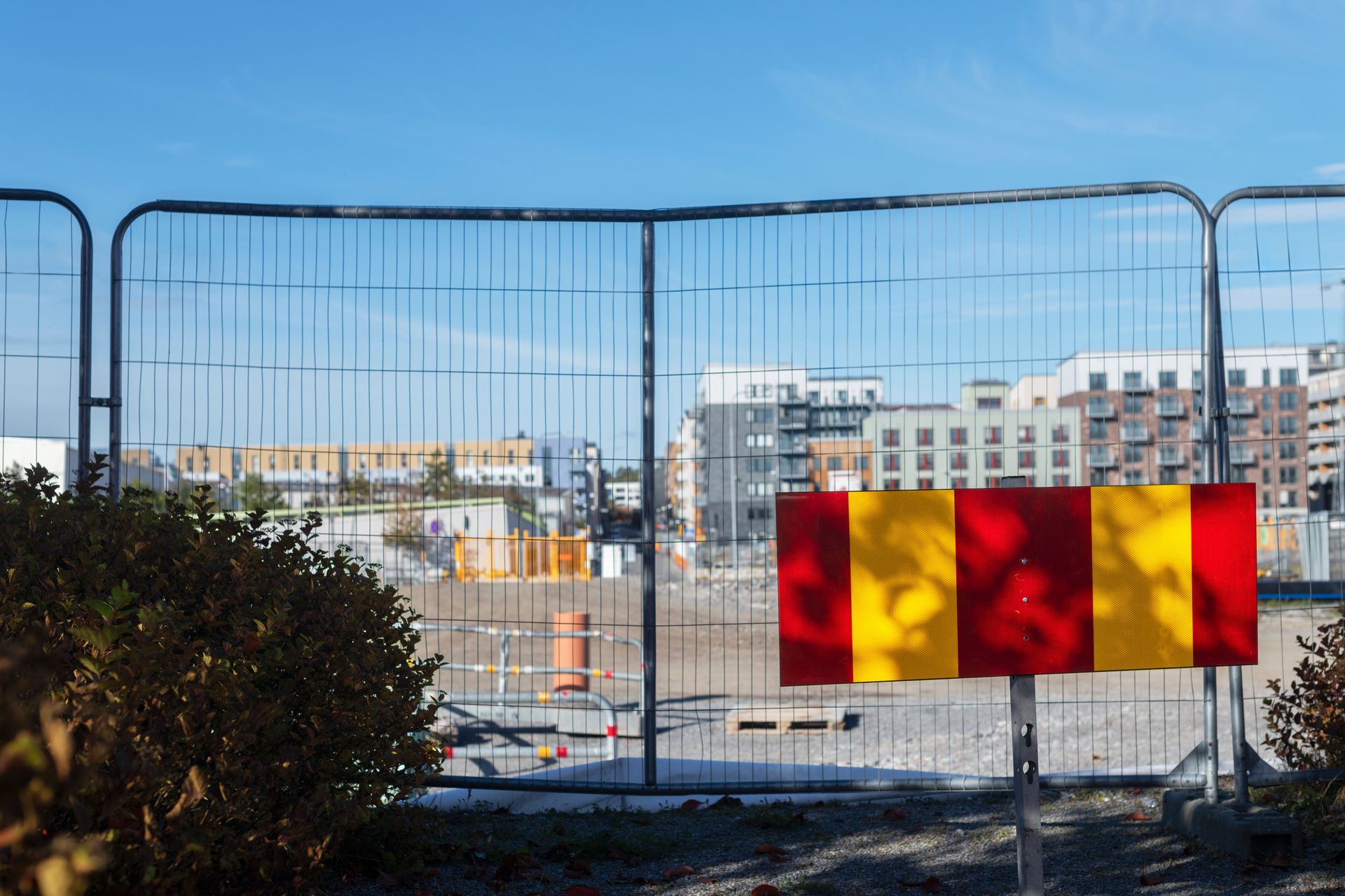 Temporary chain link fence panels with buildings on the background and blue sky. Temporary chain link fence panels with buildings on the background and blue sky.
