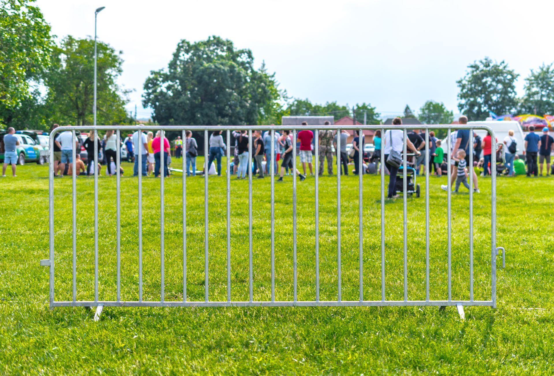 Metal crowd-control barrier set up on a grassy field during an outdoor public event.