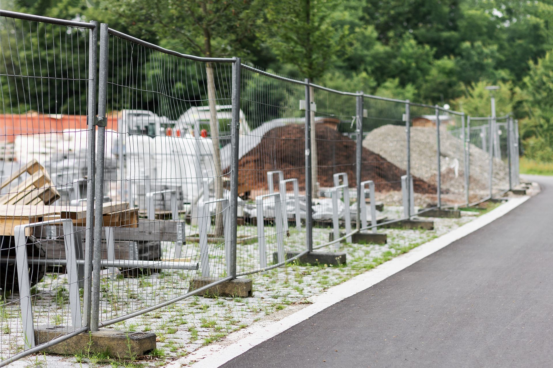 construction site fenced off with metal wire panels along a paved road.