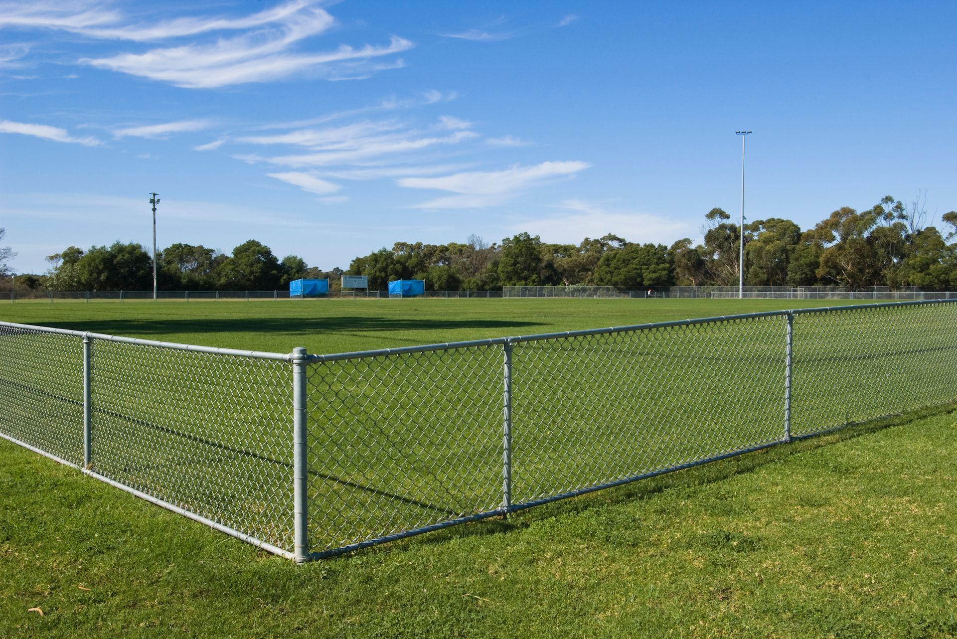 Horizontal view of an empty sports oval, with temporary chain link fence panels.