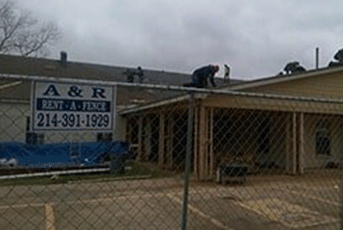 Construction workers on a building roof near a fence with an
