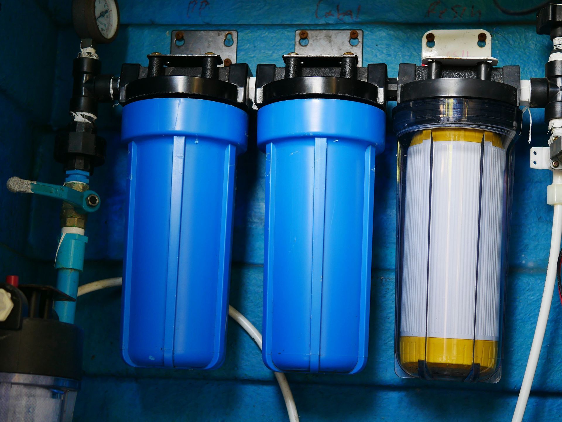 Blue water filter system with three cylindrical housings, set against a blue background.