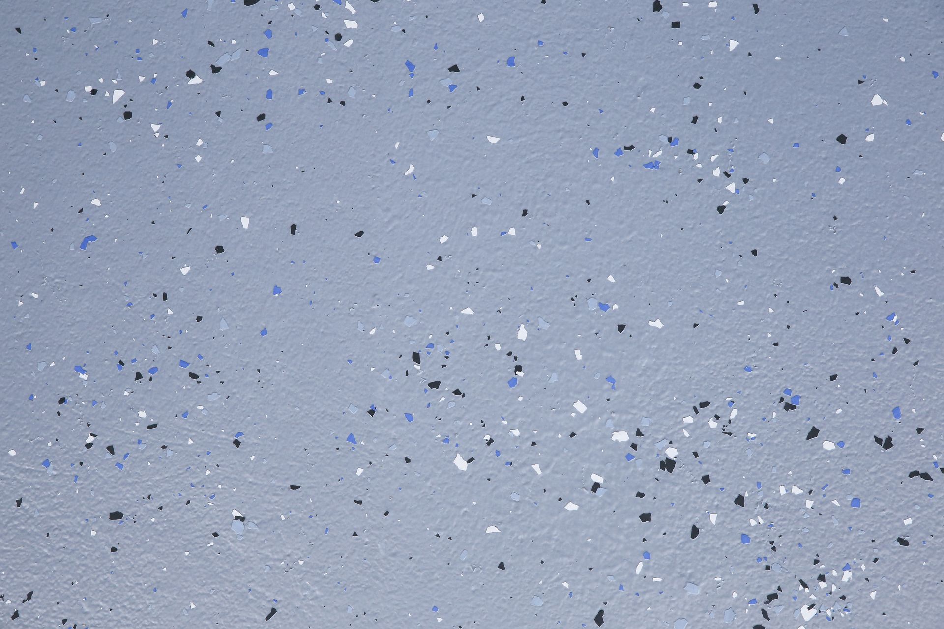 Sol de garage gris avec des flocons noirs, bleus et blancs dispersés pour un sol epoxy.