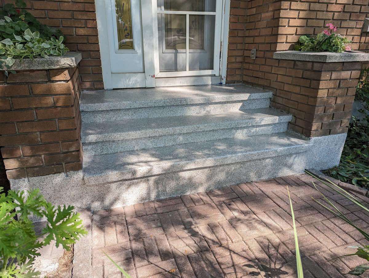 Une maison en brique avec des marches en granit menant à la porte d'entrée.