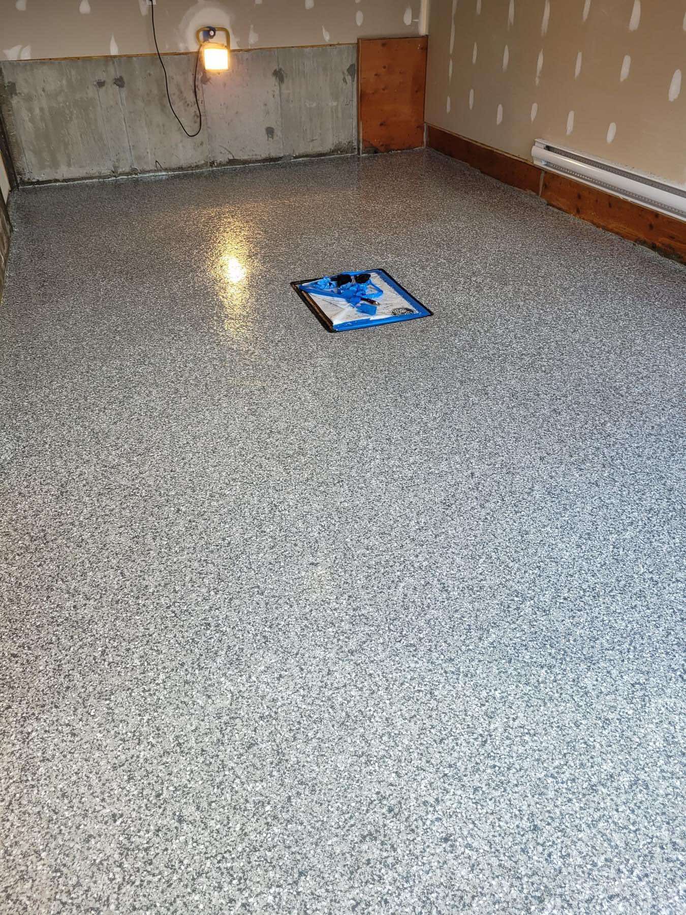 Une pièce avec un sol gris et un carré bleu dessus.