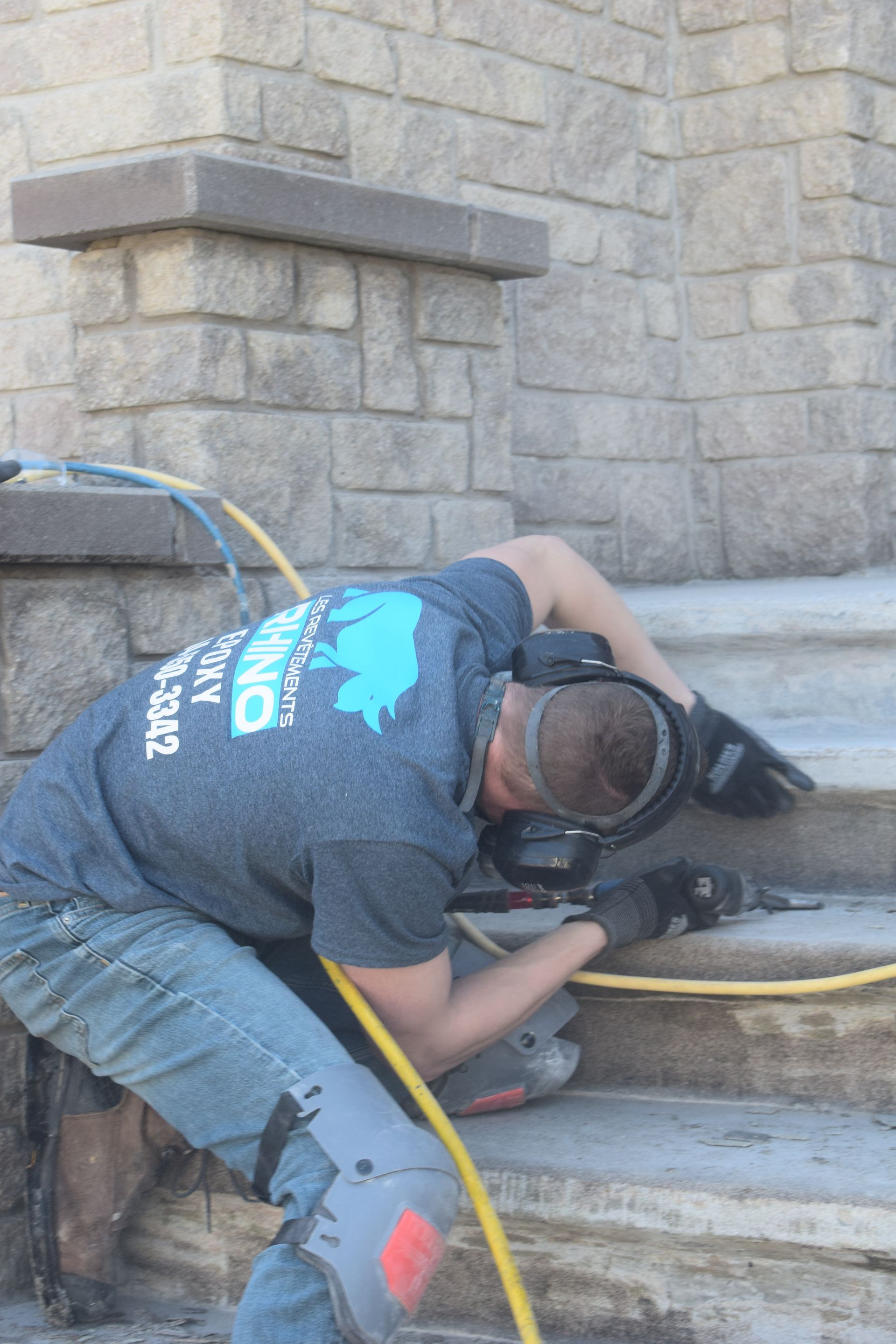 Un homme travaille sur un escalier avec un tuyau attaché à lui.