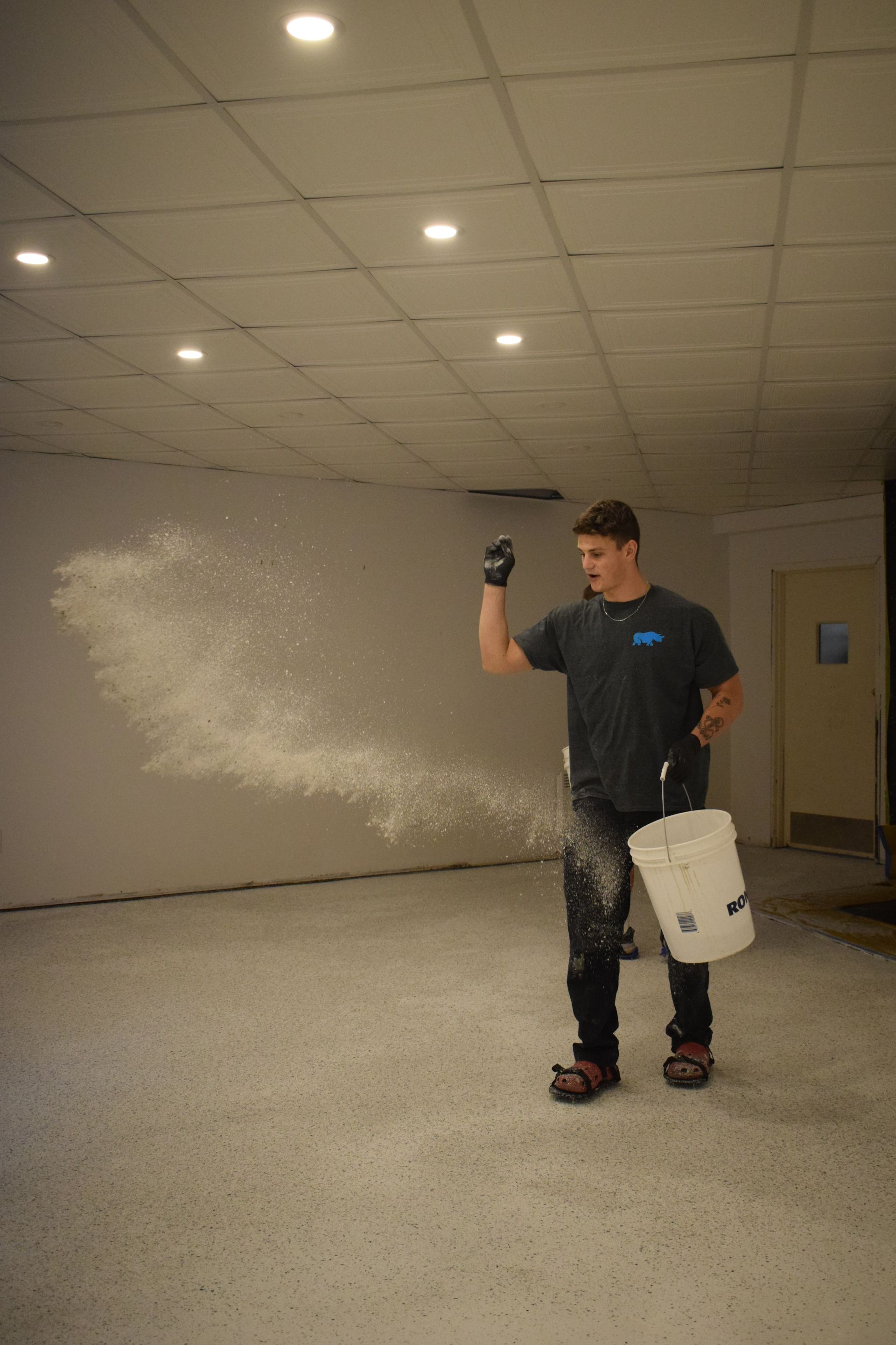 Un homme est debout dans une pièce tenant un seau blanc