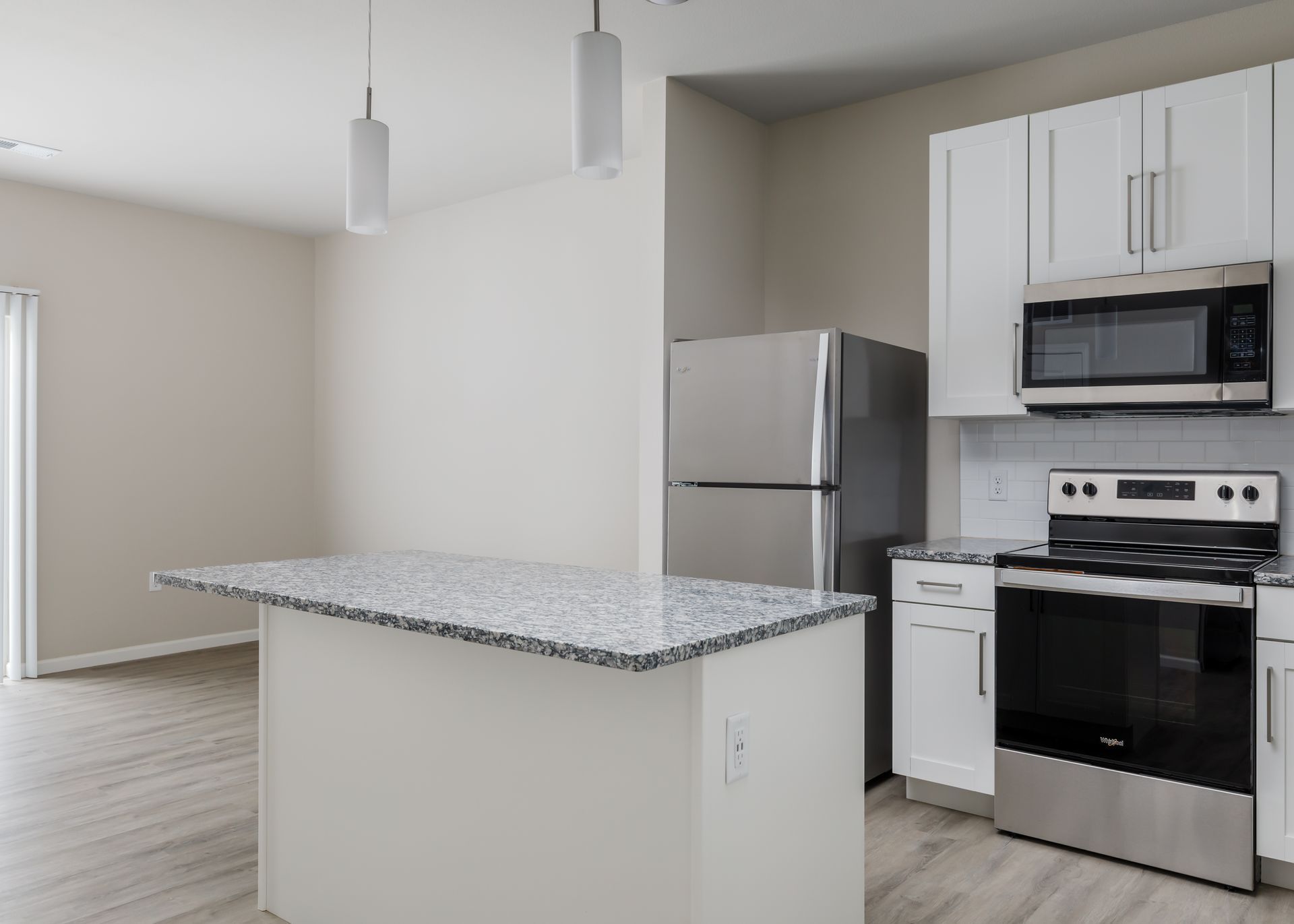 An empty kitchen with stainless steel appliances and granite counter tops