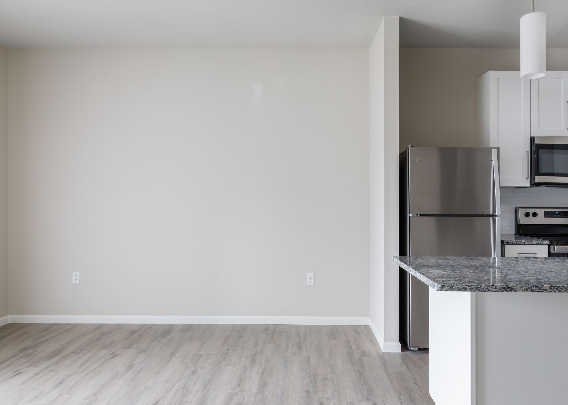 An empty kitchen with a stainless steel refrigerator , stove , and microwave.