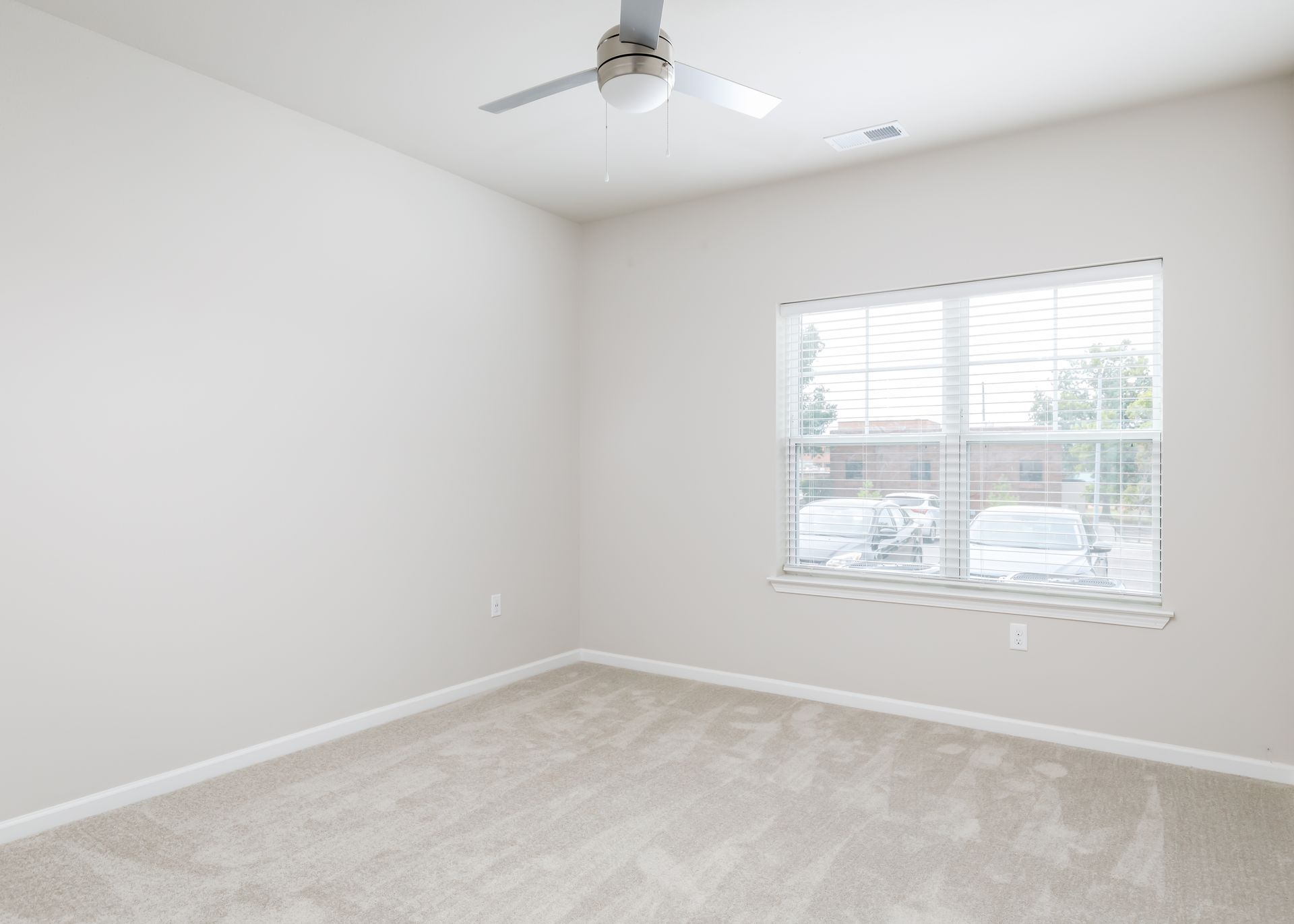 An empty bedroom with a ceiling fan and a window.