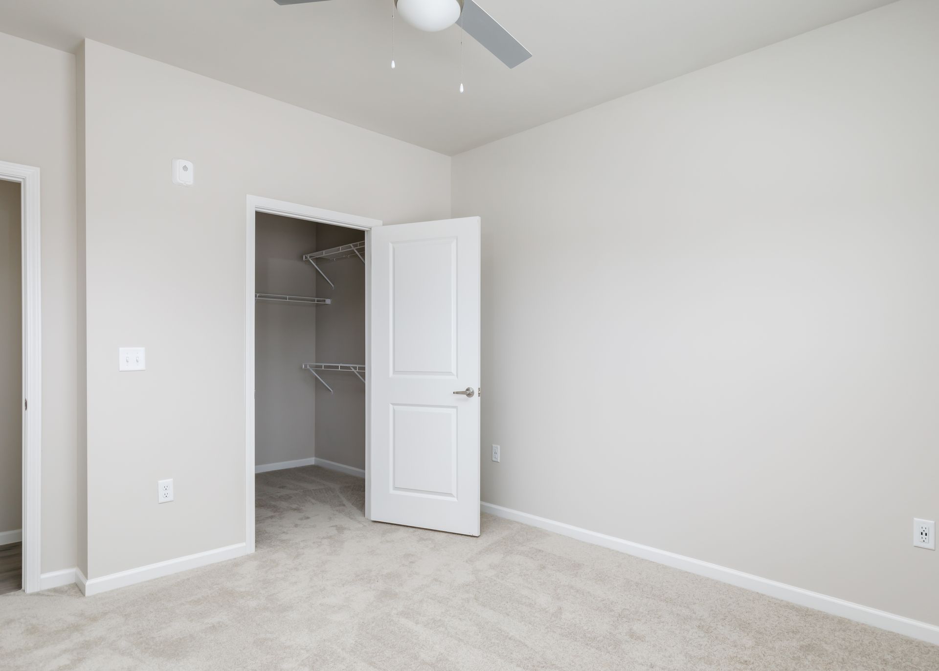 An empty bedroom with a ceiling fan and a walk in closet.