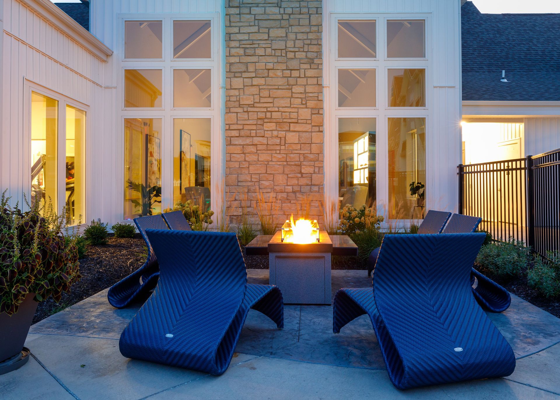 Two blue lounge chairs are sitting next to a fire pit on a patio.