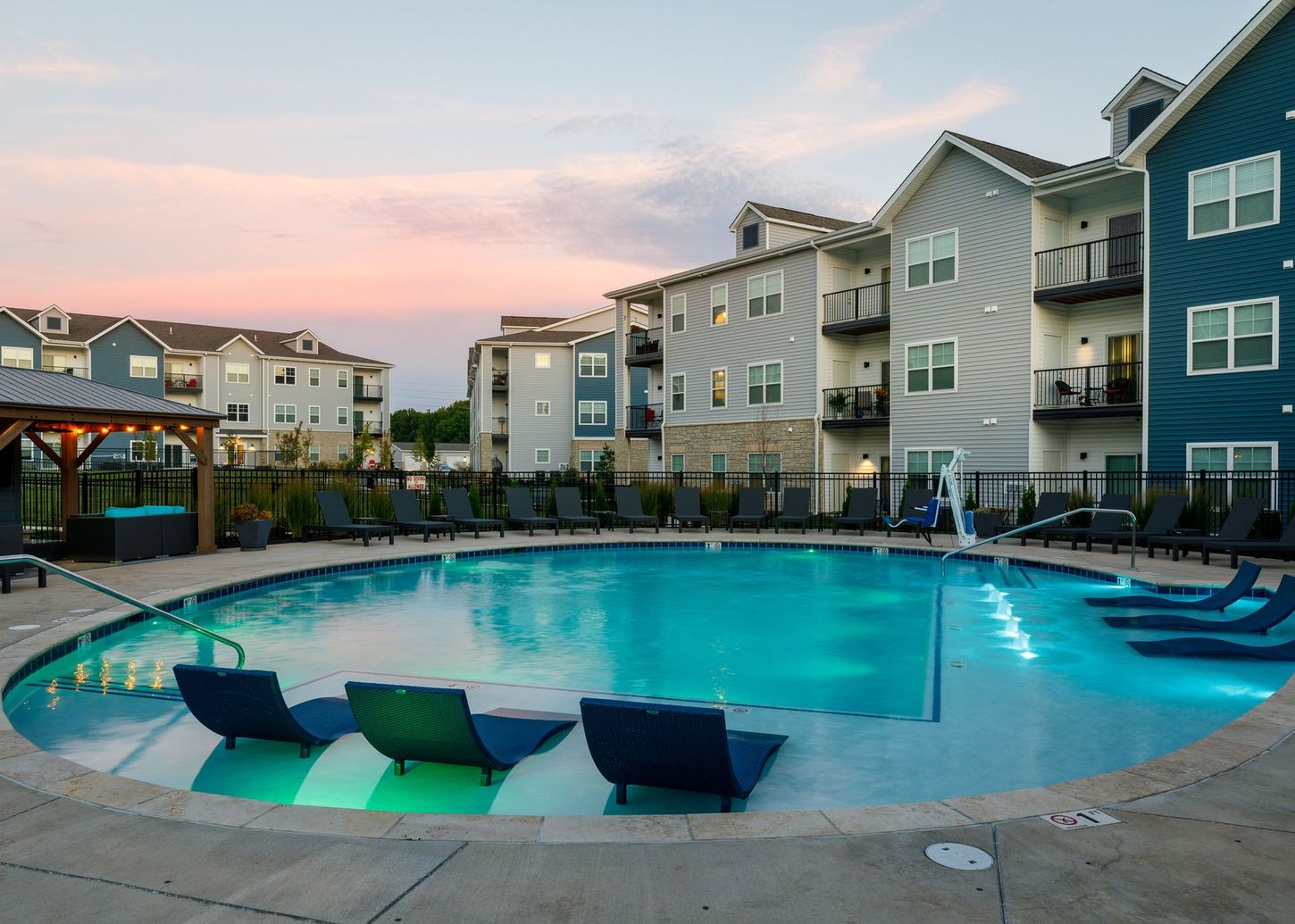 A large swimming pool with chairs around it in front of a building.