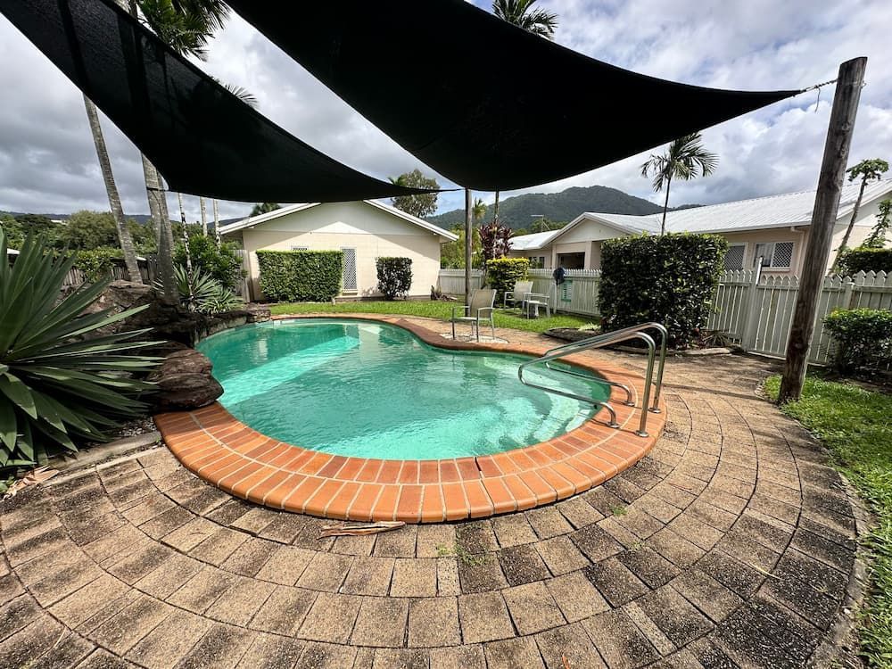 A Large Swimming Pool Is Surrounded By A Brick Patio And A Black Canopy — Cairns South Properties In Edmonton, QLD
