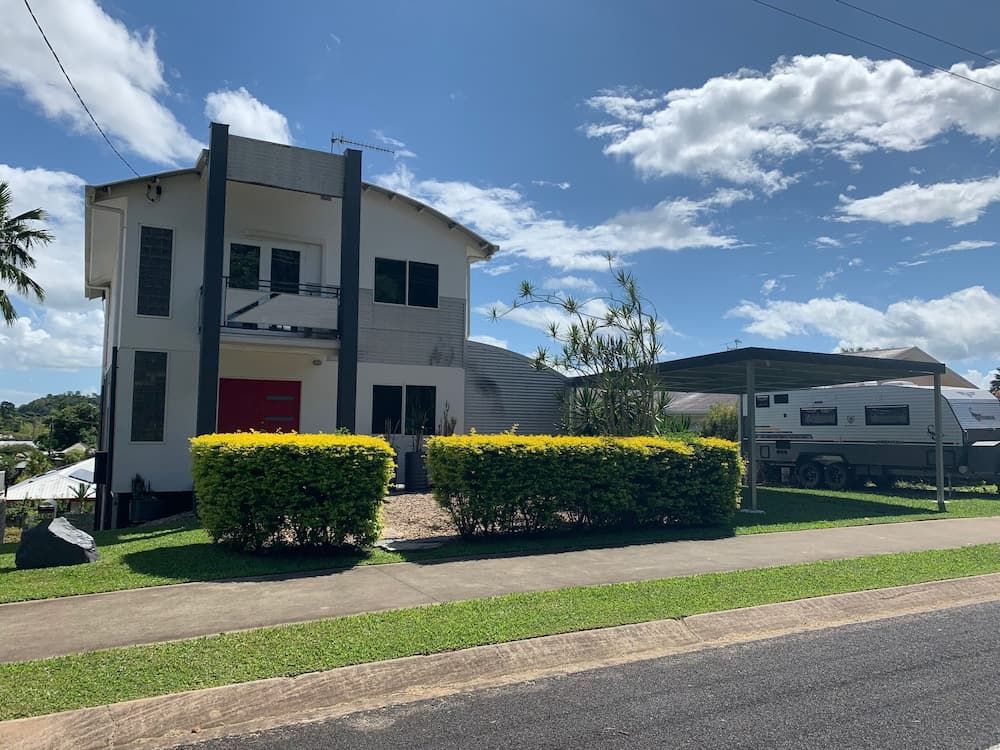 A Large White House With A Trailer Parked In Front Of It — Cairns South Properties In Cairns, QLD