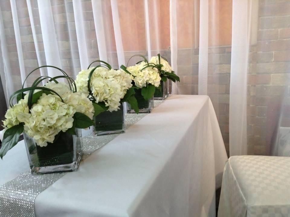 Une table avec des fleurs blanches dans des vases dessus.